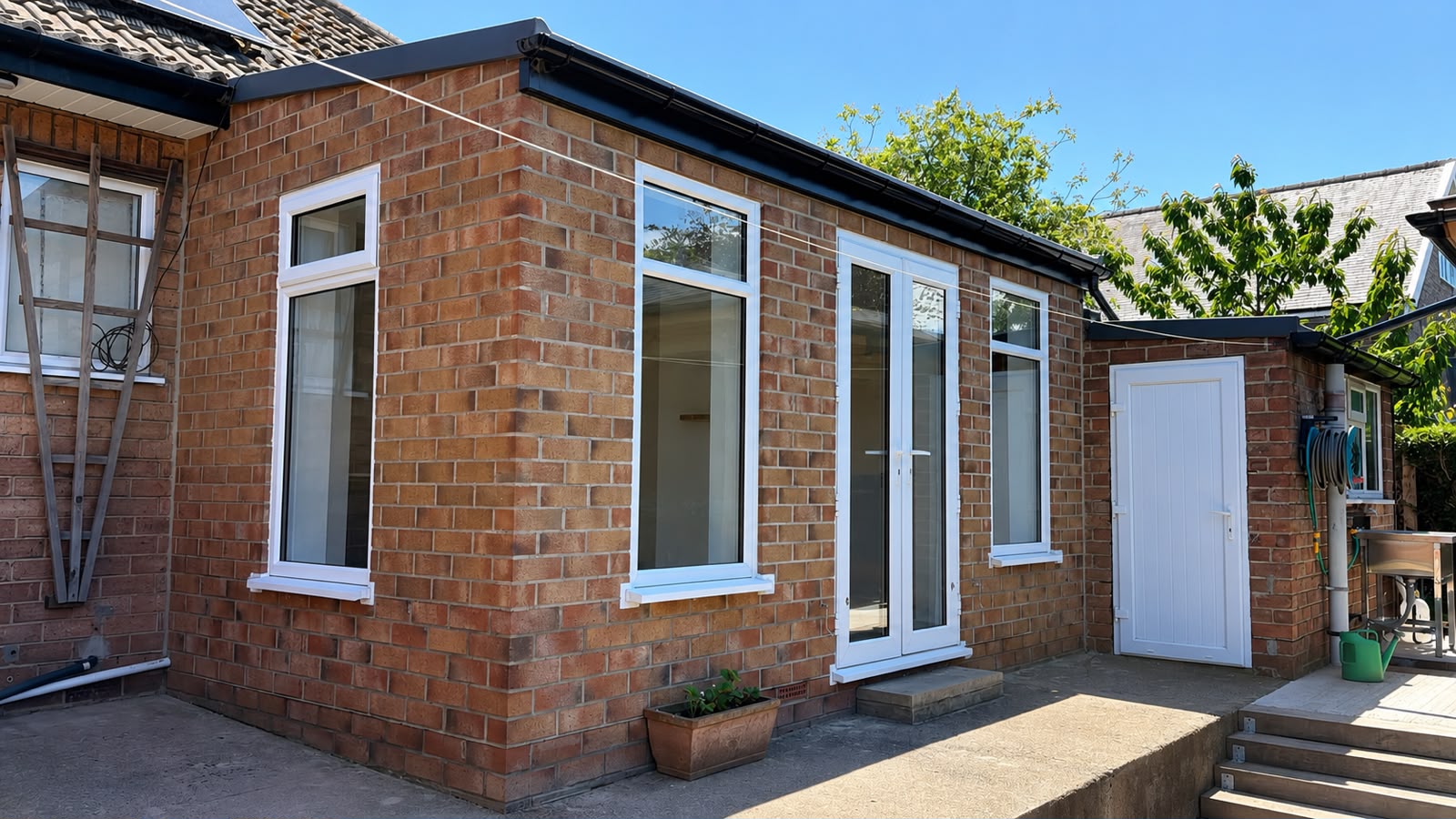The finished conversion from the garden — brick walls, new windows and french doors under a proper insulated roof