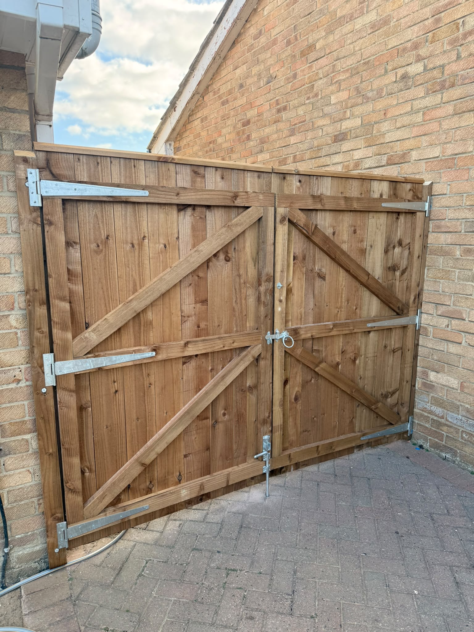 A pair of braced timber driveway gates hung on heavy galvanised hinges